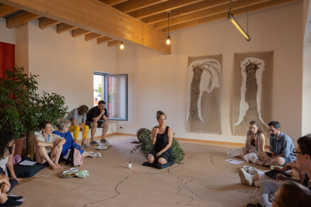 L'artiste Samah Hijawi se tient au centre, sur un sol de papier qui lui permet de dessiner, entourée des publics.