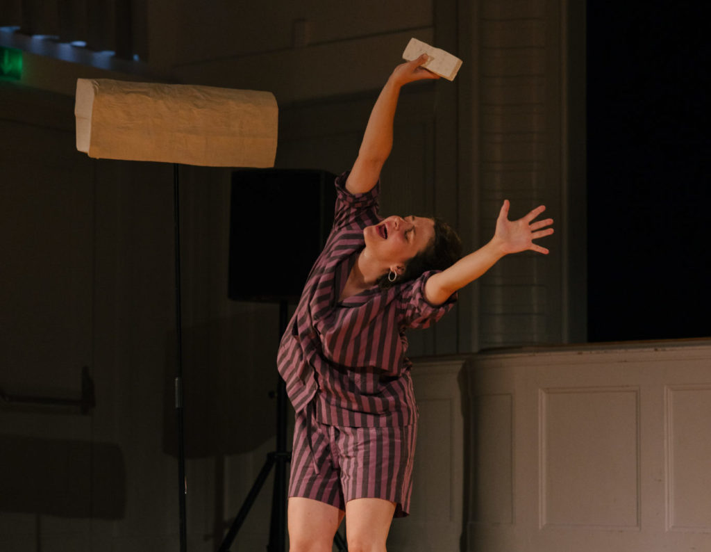 The artist Annina Polivka stands on the seen the arms in the air, imagining air refreshing her.