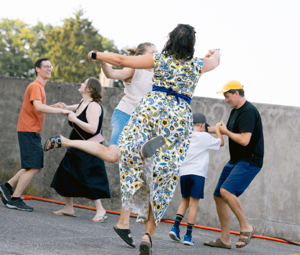 On voit des couples de personne danser la valse. Au premier plan, on voit une femme de dos avec sa partenaire qui a juste le bout d'un pied par terre. Elle semble élevée dans les airs.