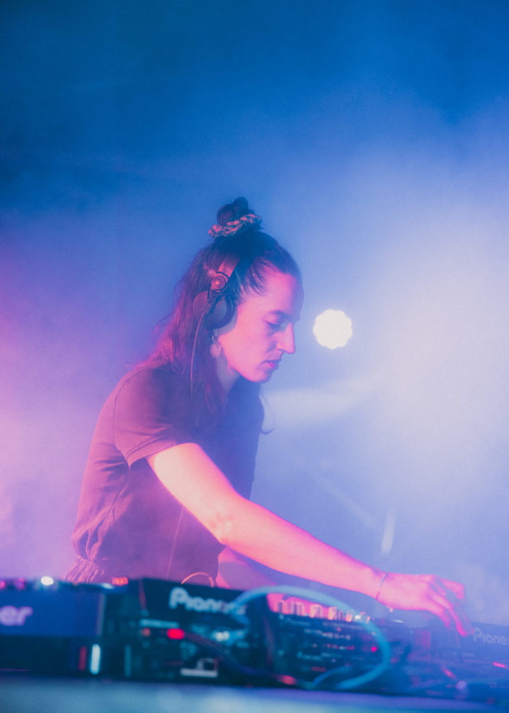 We can see the DJette awka mix sounds. Her right arm is visible and she wears black headphones.