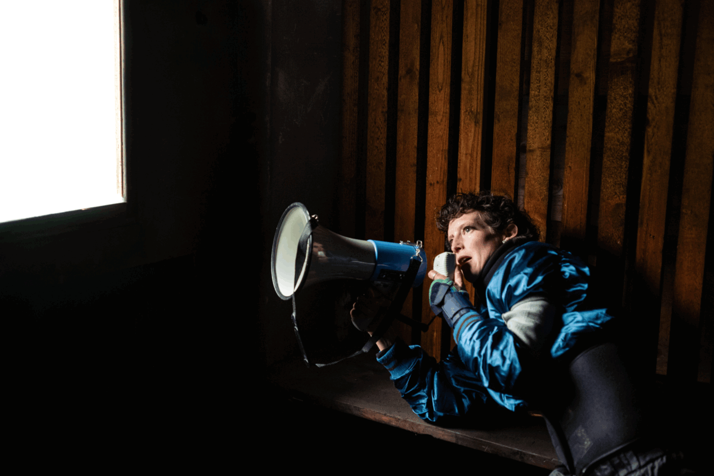 Elise Perrin est allongée et parle dans un mégaphone.