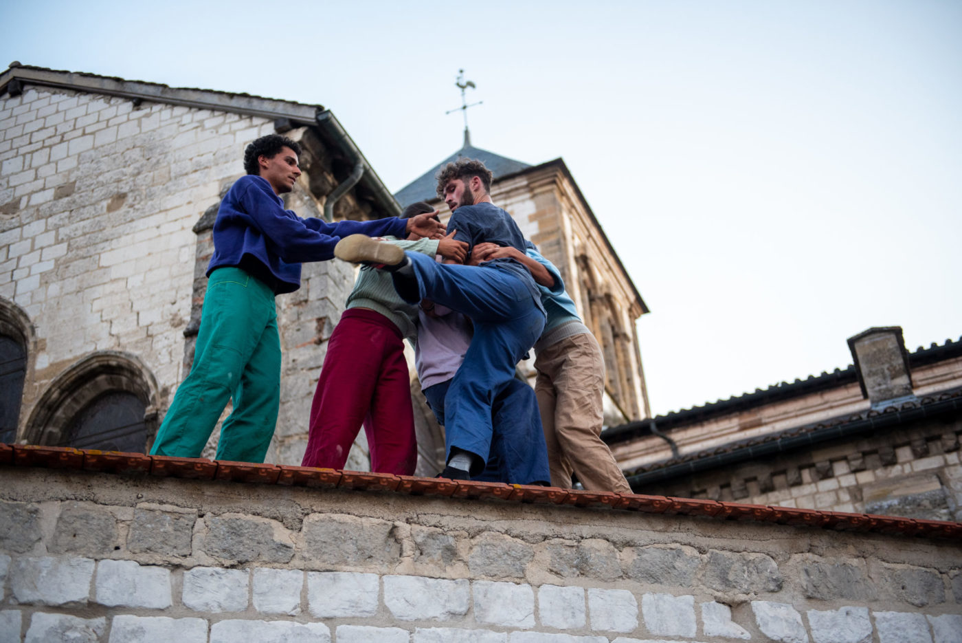 Les 5 acrobates de la horde dans les pavés sont sur le toit d'un immeuble qui ressemble à une église. Ils font des acrobaties.