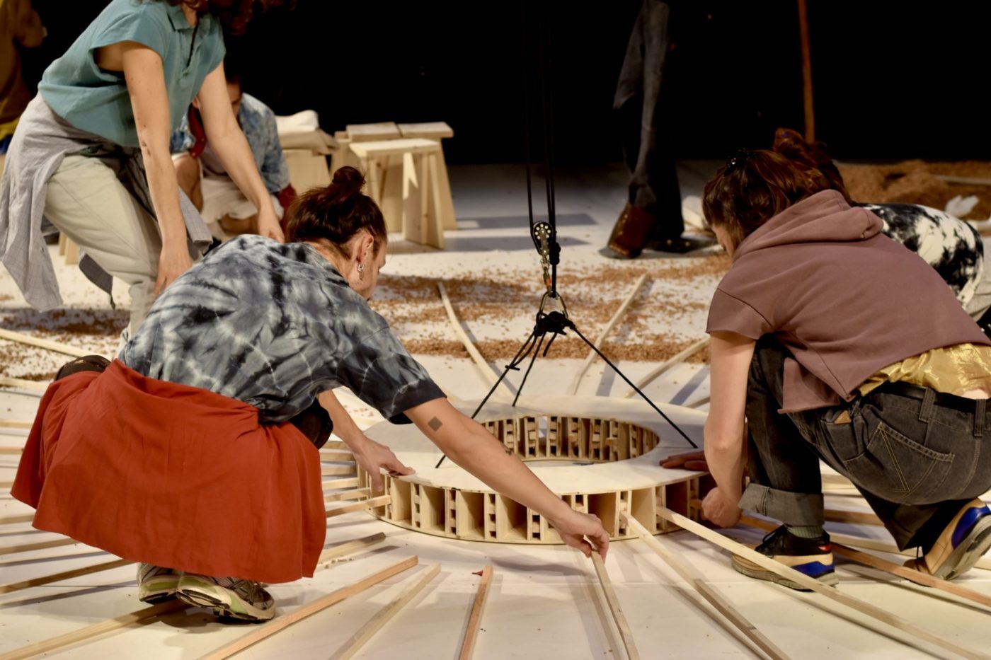 Plusieurs personnes sont en train de fabriquer une structure en bois sur scène.