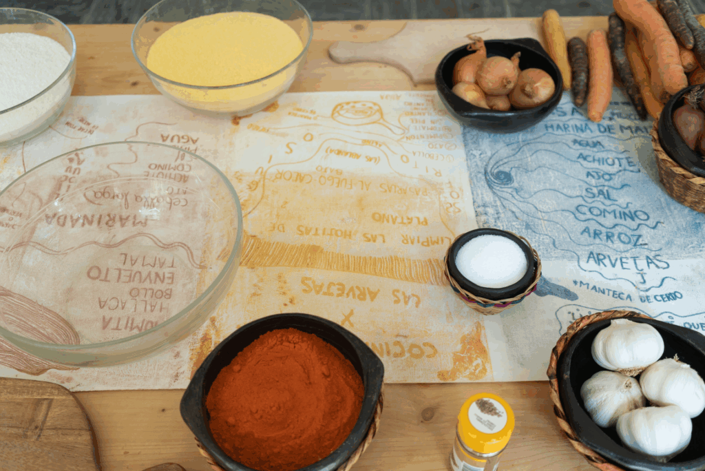 Il y a plusieurs ingrédients disposés sur une table en bois. Ce sont les ingrédients nécessaires à la préparation du tamal.